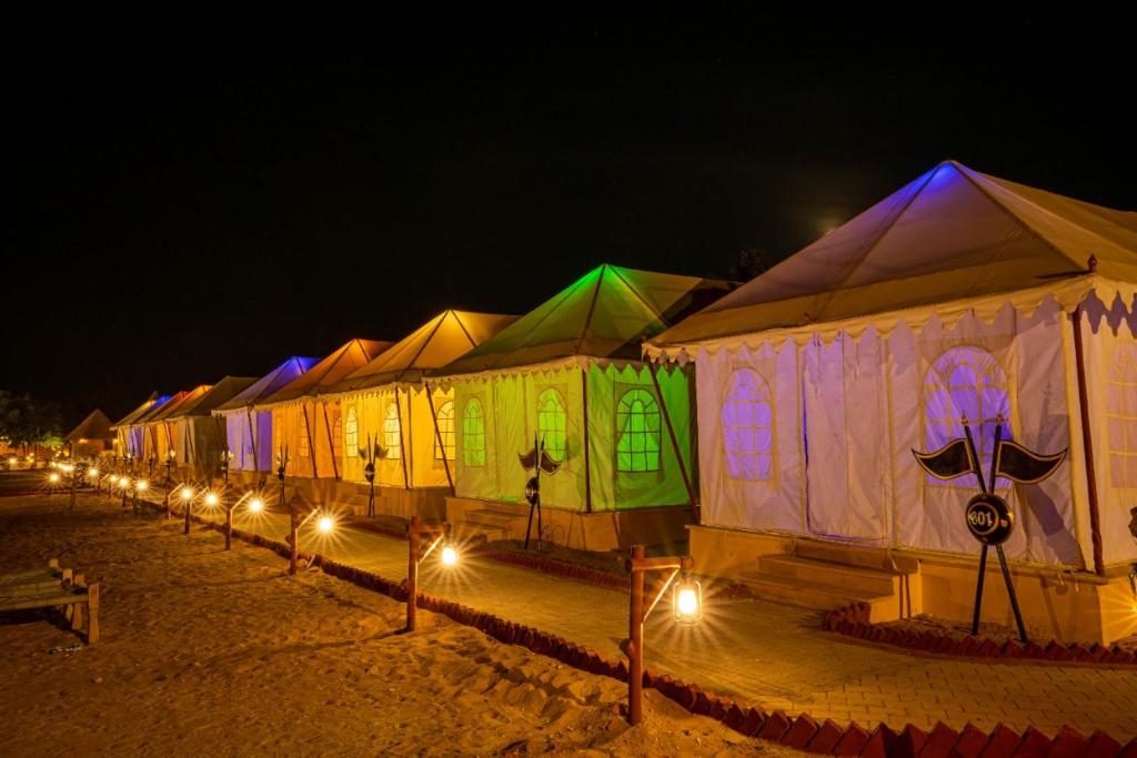 una fila de tiendas de campaña con luces por la noche en Jaisalmer Night Safari Camp, en Jaisalmer