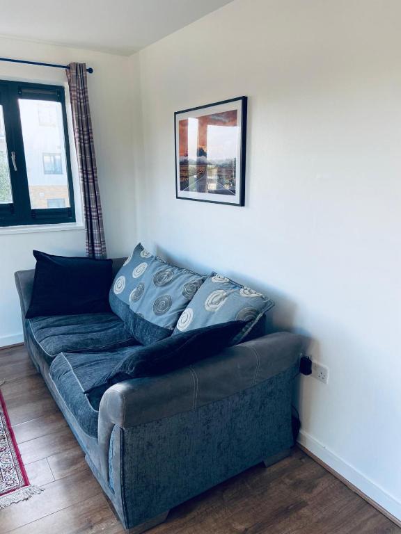 a couch with pillows on it in a living room at Alba, 2 Bed Flat, by Grays Station, Free Parking in Stifford