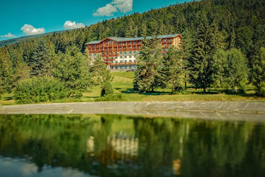 a building on a hill next to a body of water at Hotel Partizán in Tale