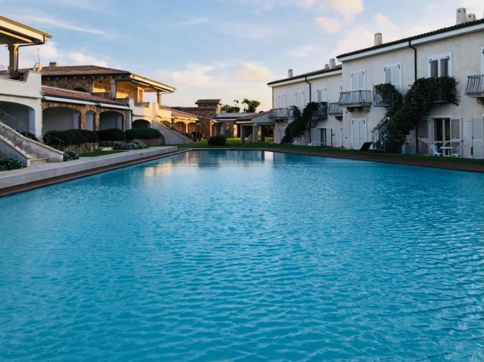 ein großer blauer Pool vor einigen Gebäuden in der Unterkunft LOTUS Wellness Apartment - Resort Ginestre - Palau - Sardinia in Palau