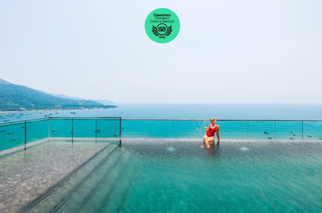 una mujer parada en el agua en una piscina en The Code Hotel & Spa Da Nang en Da Nang