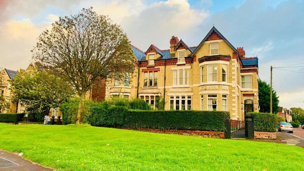 a large house with a green lawn in front of it at Single Room Shared bathroom Free Street Parking Near Anfield LFC in Liverpool