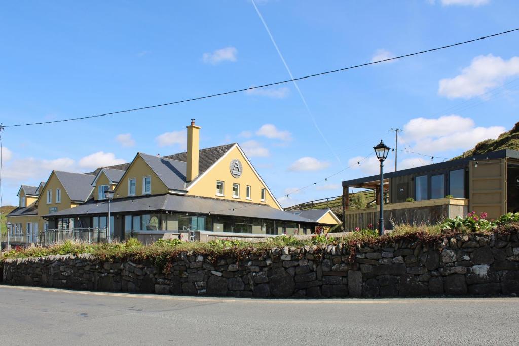 een groot geel huis met een stenen muur bij Doolin Inn in Doolin