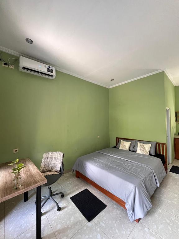 a green bedroom with a bed and a desk and a bed sidx sidx at Nomad Cottage in Amed