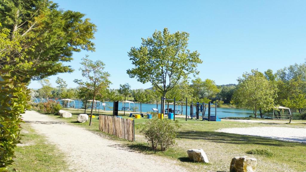 um caminho ao lado de um parque com um parque infantil em Mobil Home vue sur le lac dans un camping 4 étoiles à Cadenet em Cadenet