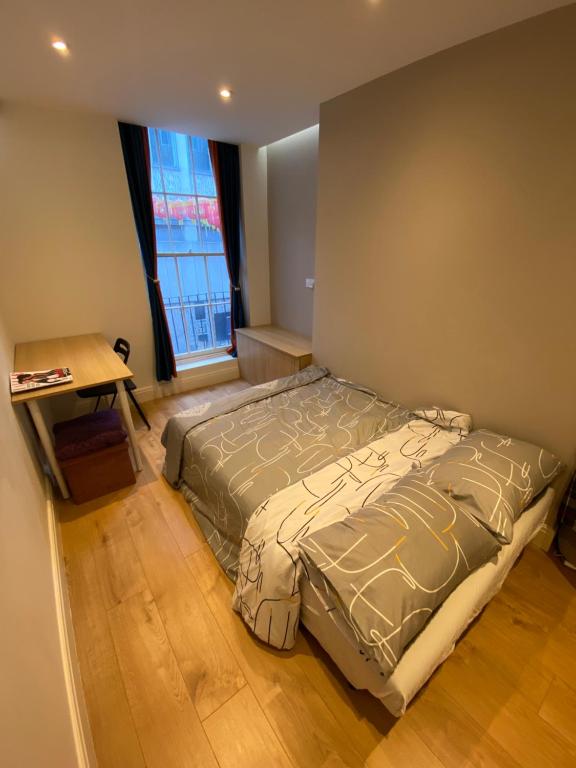 a bedroom with a bed and a desk and a window at Not Very Quiet but best location in London