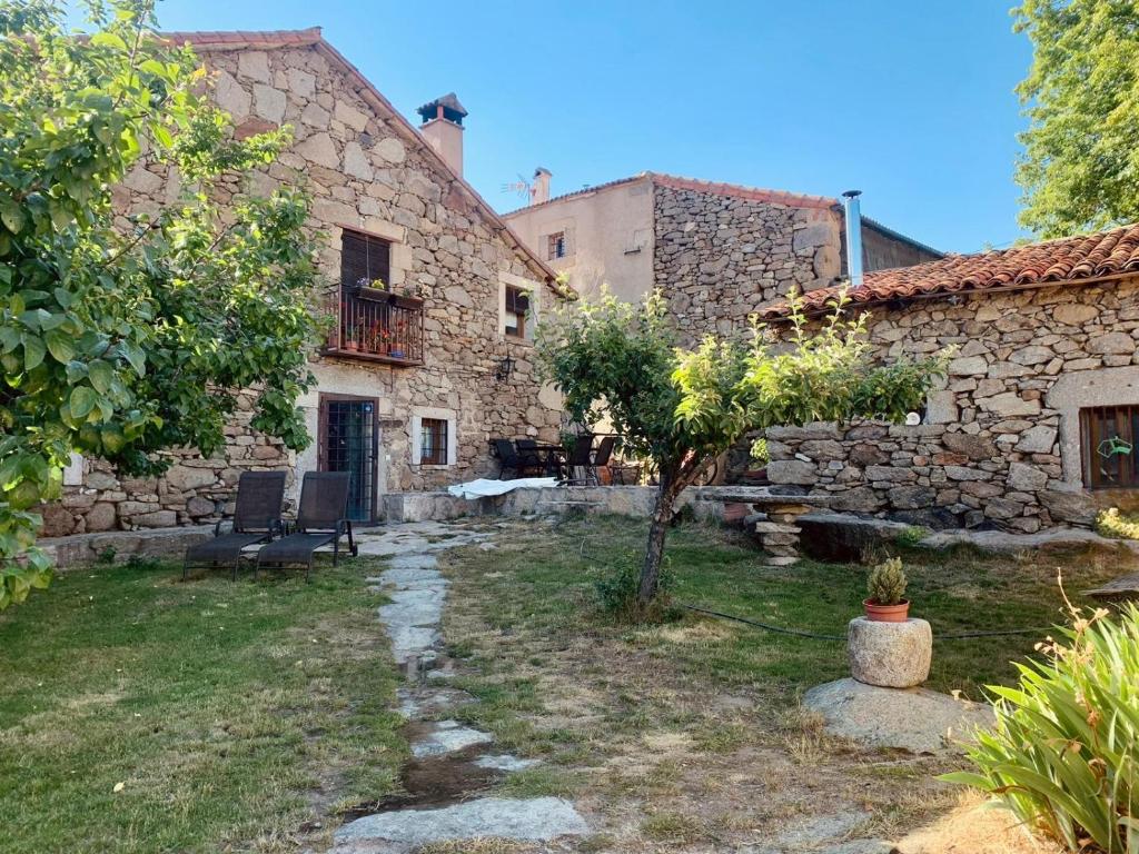 una casa de piedra con un árbol en el patio en Casa Rural La Casa de Piedra, en Navarredonda de Gredos