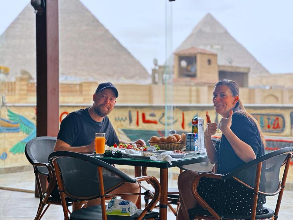 King Pyramids View Hotel في القاهرة: رجل وامرأة يجلسون على طاولة طعام