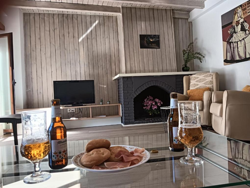 a living room with a table with a plate of food and two glasses at La Casa de la Plaza in Güéjar-Sierra