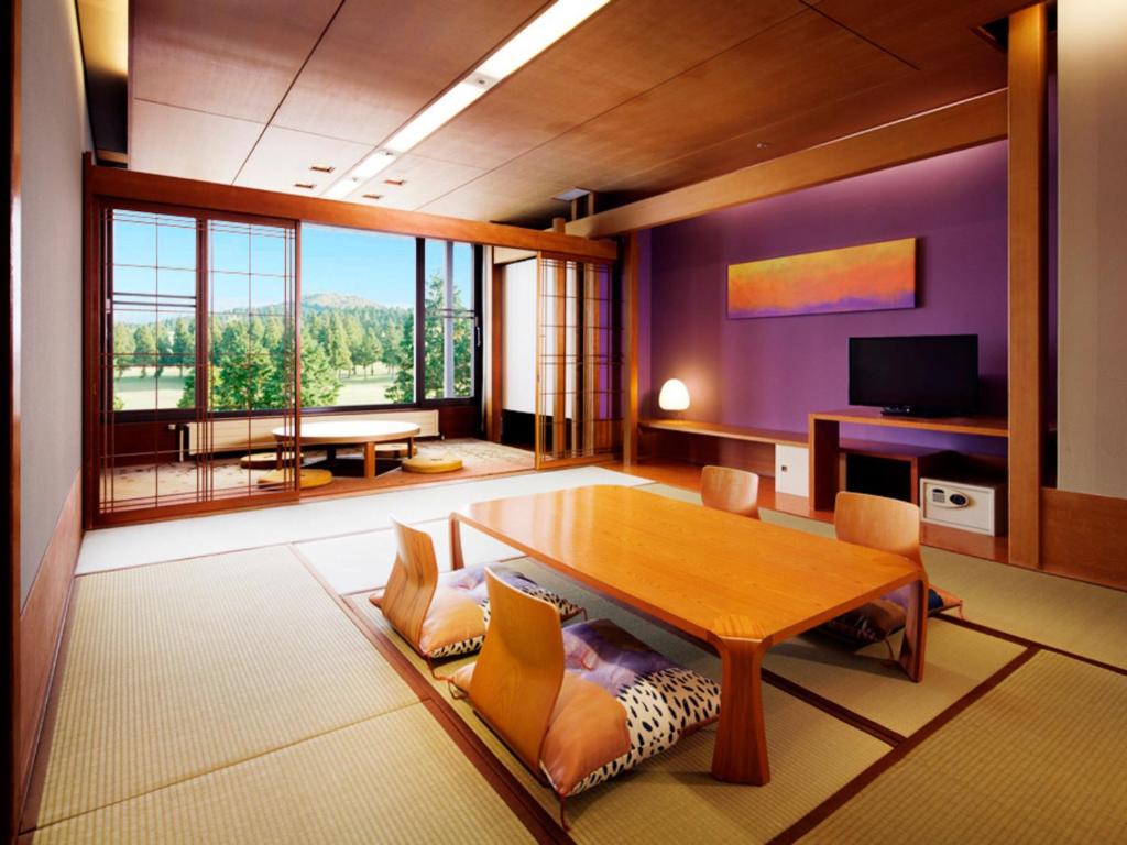 a living room with a table and a large window at Hakone Yunohana Prince Hotel in Hakone