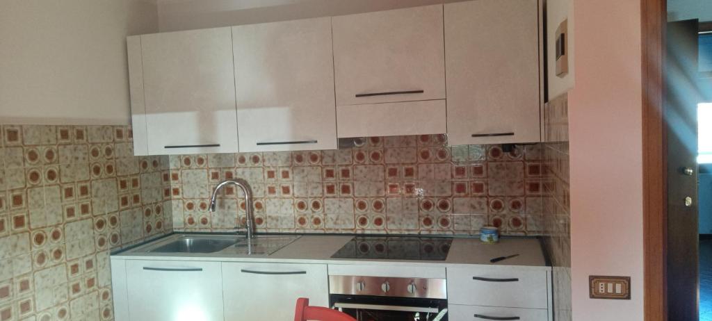 Una cocina con gabinetes blancos y un fregadero. en Gian maria Vacanze, en Altopascio