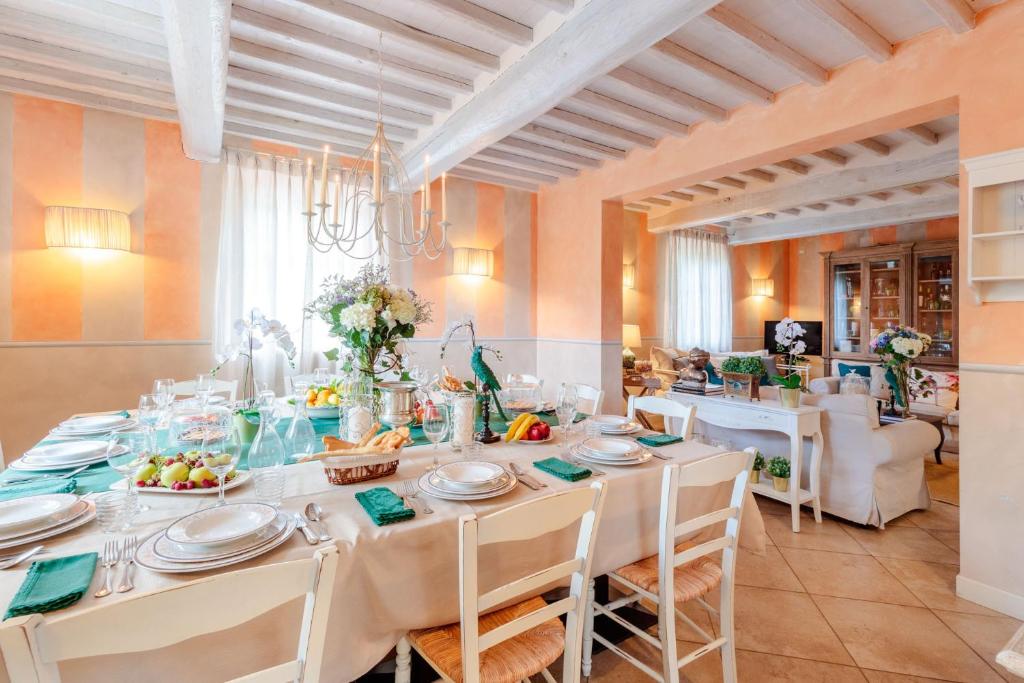 une salle à manger avec une grande table et des chaises blanches dans l'établissement Casolare dei Colli, Panoramic Private Pool, Lavish Interiors and a Gourmet Kitchen, à Camaiore