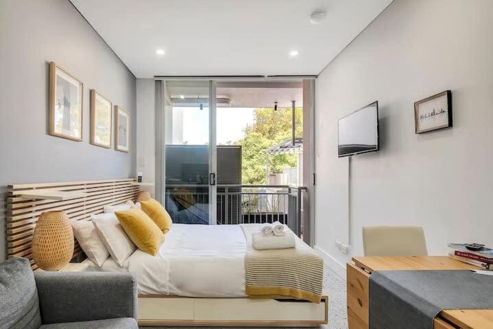 a bedroom with a bed and a couch and a window at Studio in Crown St - Private Balcony & Aircon in Sydney