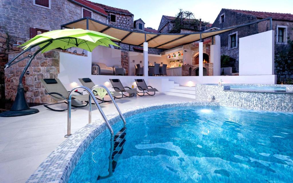 a swimming pool with an umbrella next to a house at Holiday Home Pitve in Pitve