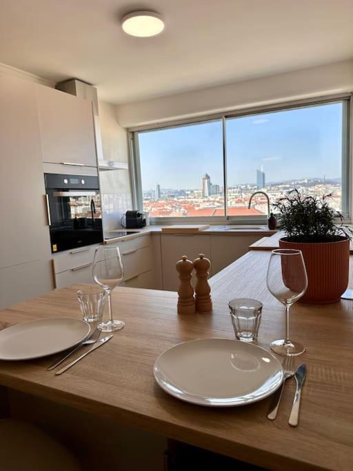 - une table avec deux assiettes et des verres à vin dans l'établissement Le Panoramic, à Villeurbanne