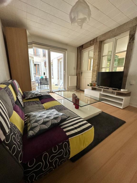 a living room with a bed and a tv at Epinal Hyper Centre, Place des Vosges T2 avec terrasse et salon de jardin. in Épinal