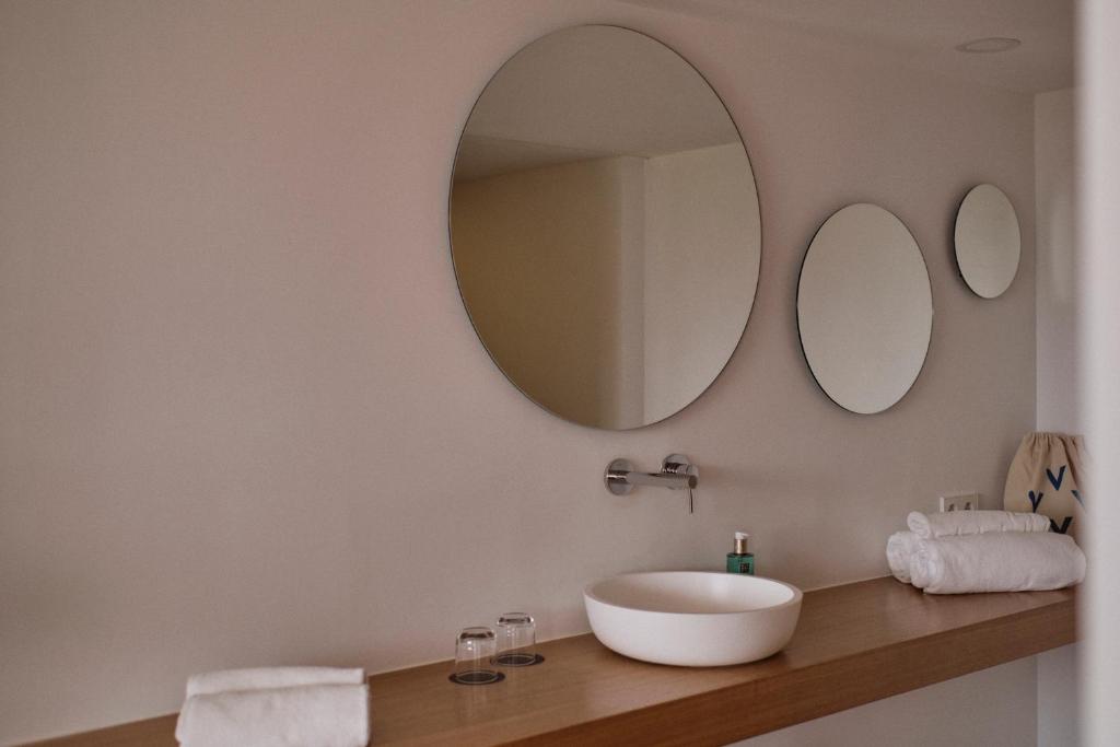 a bathroom with a sink and two mirrors on the wall at Las Gaviotas Suites Hotel & Spa in Playa de Muro