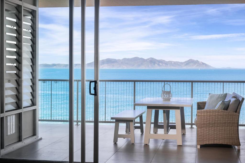 balkon ze stołem i widokiem na ocean w obiekcie Grand Mercure Apartments Magnetic Island w mieście Nelly Bay