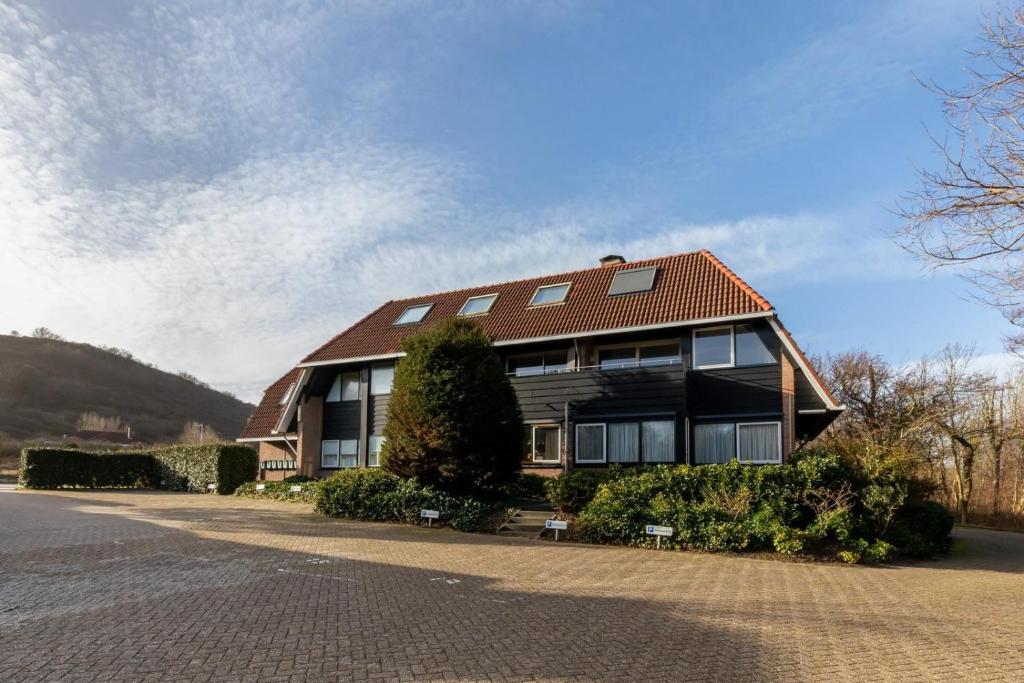 una casa grande con techo rojo en una calle en Appartement - Duinweg 117-14 Zoutelande, en Zoutelande