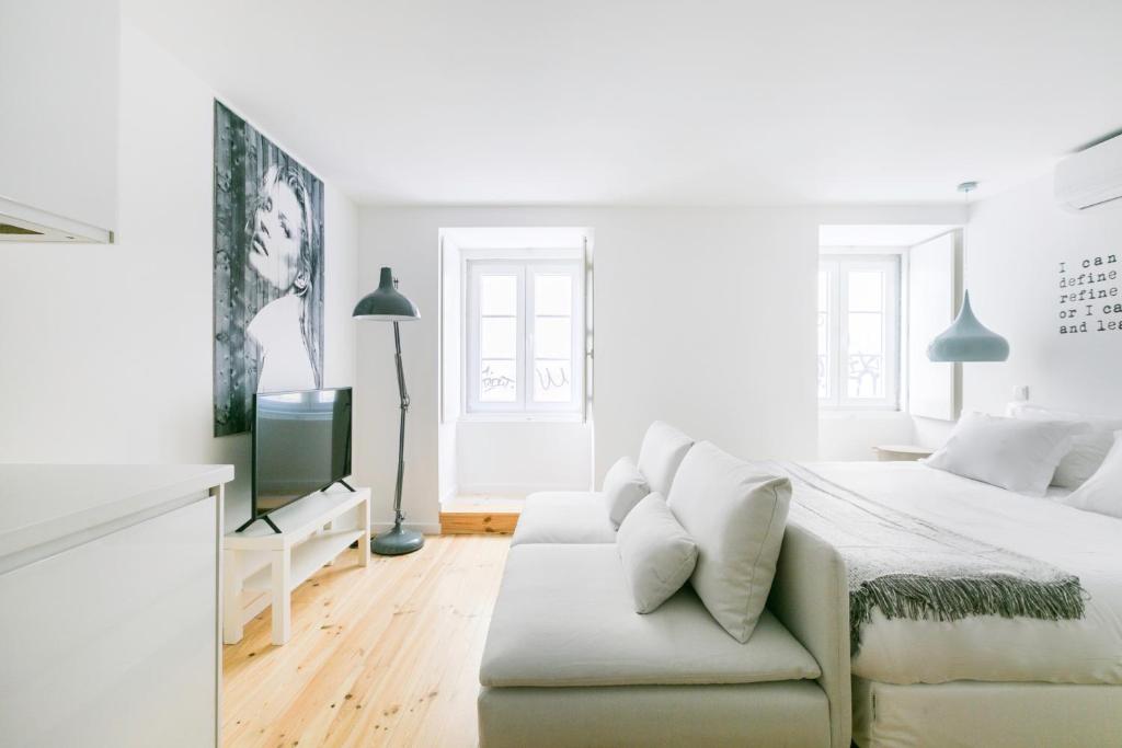 ein weißes Schlafzimmer mit einem Bett und einem Sofa in der Unterkunft MY LX FLAT Bairro Alto Design Apartments in Lissabon