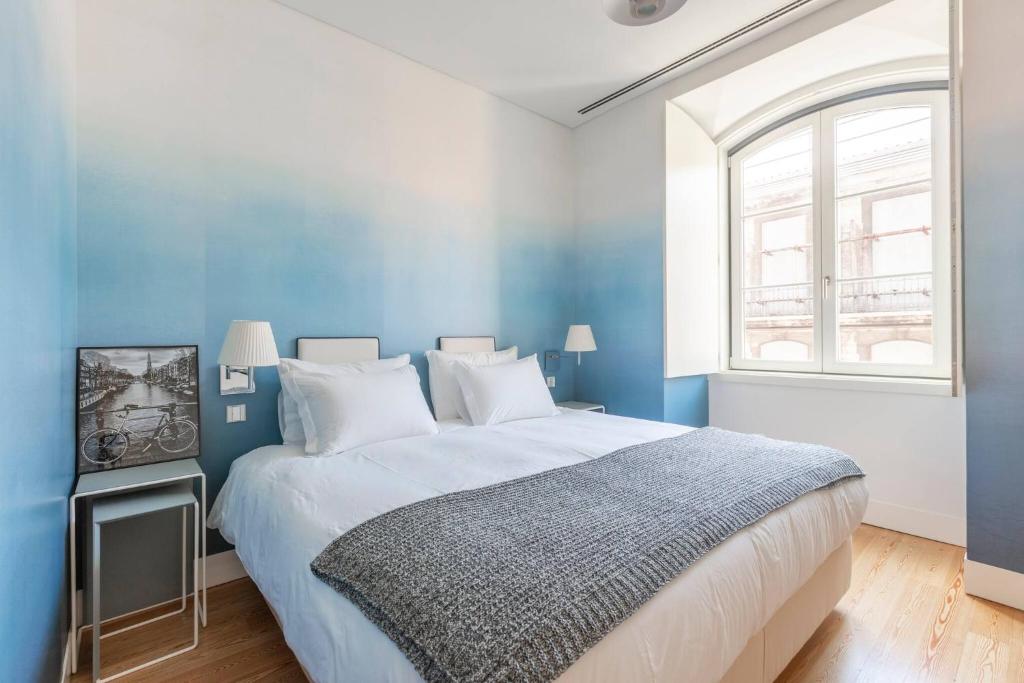 niebieska sypialnia z dużym łóżkiem i oknem w obiekcie MY LX FLAT Luxury Chiado Design Apartment w Lizbonie
