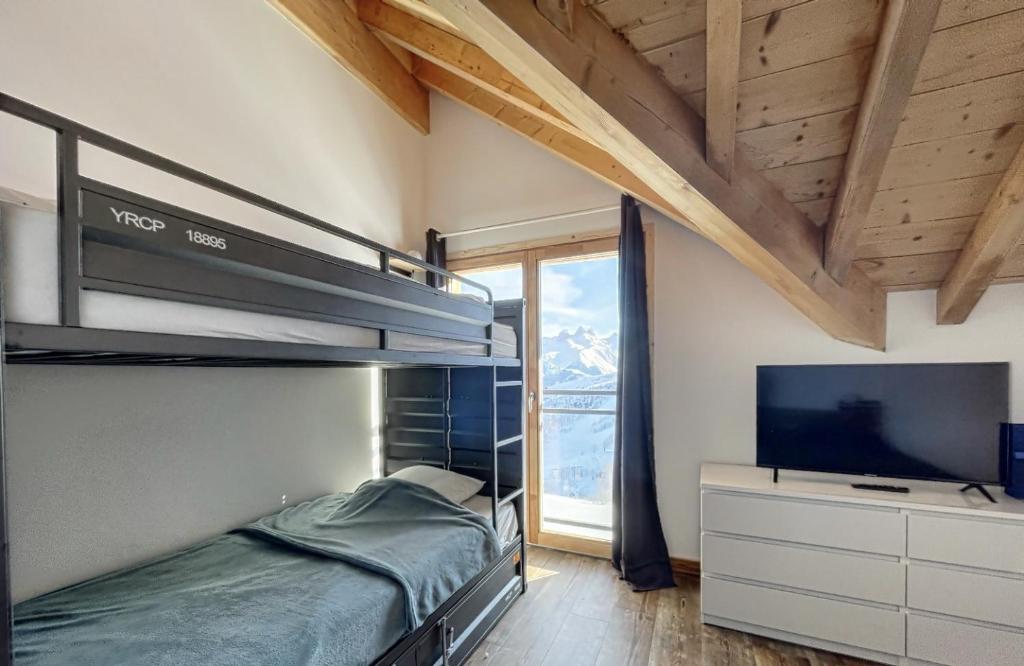 a bedroom with a bunk bed and a flat screen tv at Chalet Le Mauntenrojji - skis aux pieds in La Toussuire