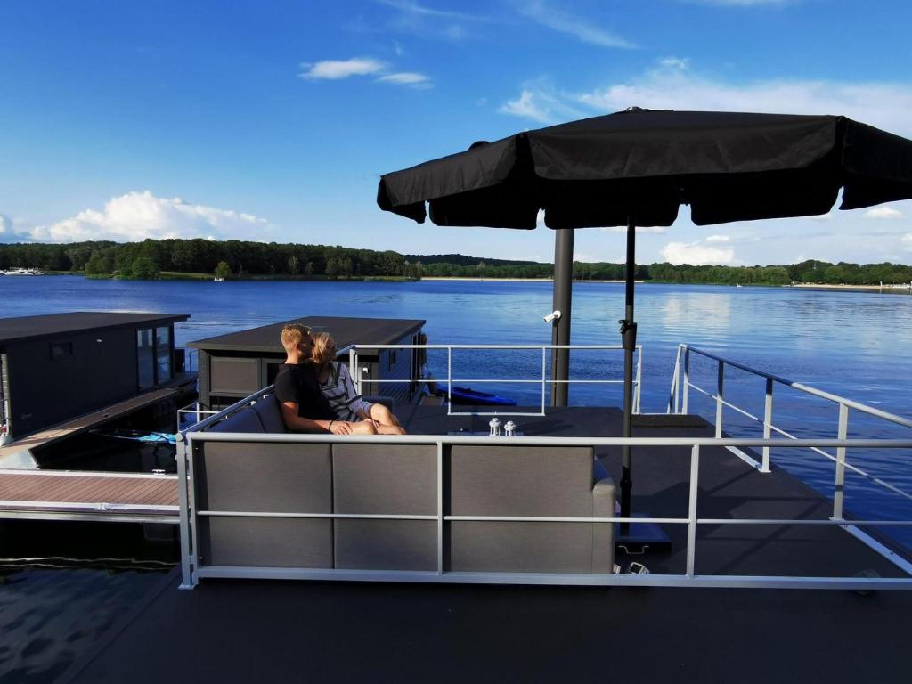 a woman sitting on the back of a boat with an umbrella at Houseboat Marina Mookerplas 4-6 persons roof terrace in Plasmolen