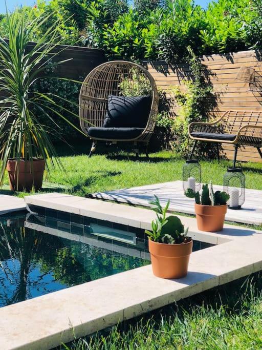 une piscine avec des chaises et des plantes en pot dans une cour dans l'établissement Villa Piscine - 5 min du centre historique d'Aix en Provence, à Aix-en-Provence