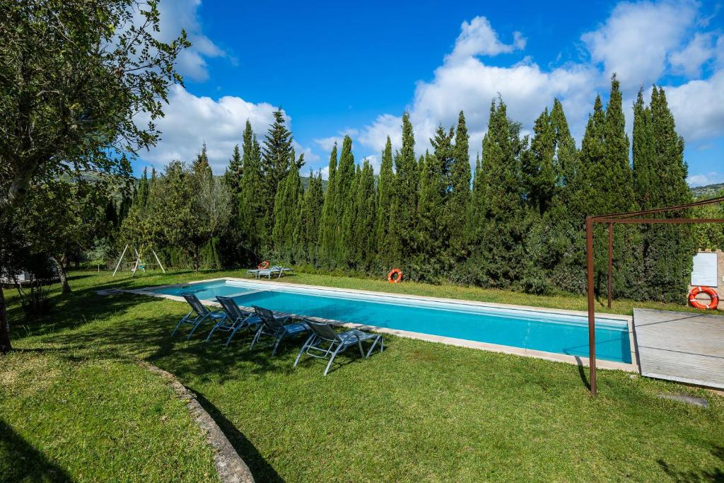 een zwembad in een tuin met stoelen en bomen bij Sa Soll in Sant Llorenç des Cardassar