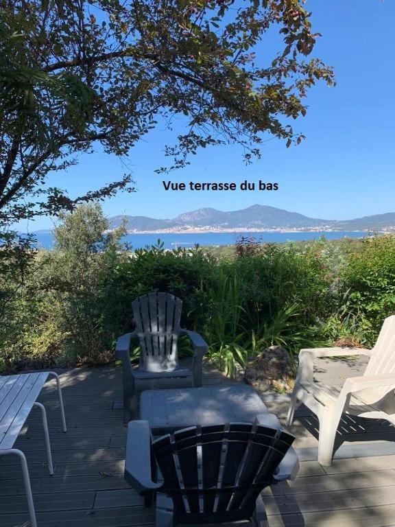 a patio with two chairs and a bench and the ocean at Villa La Viva Porticcio in Porticcio