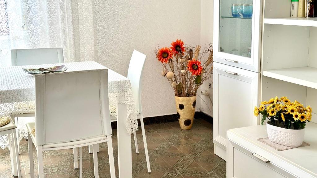 kuchnia ze stołem i krzesłami oraz wazonem kwiatów w obiekcie SE081 - Marotta, trilocale a 100 mt dal mare w mieście Marotta