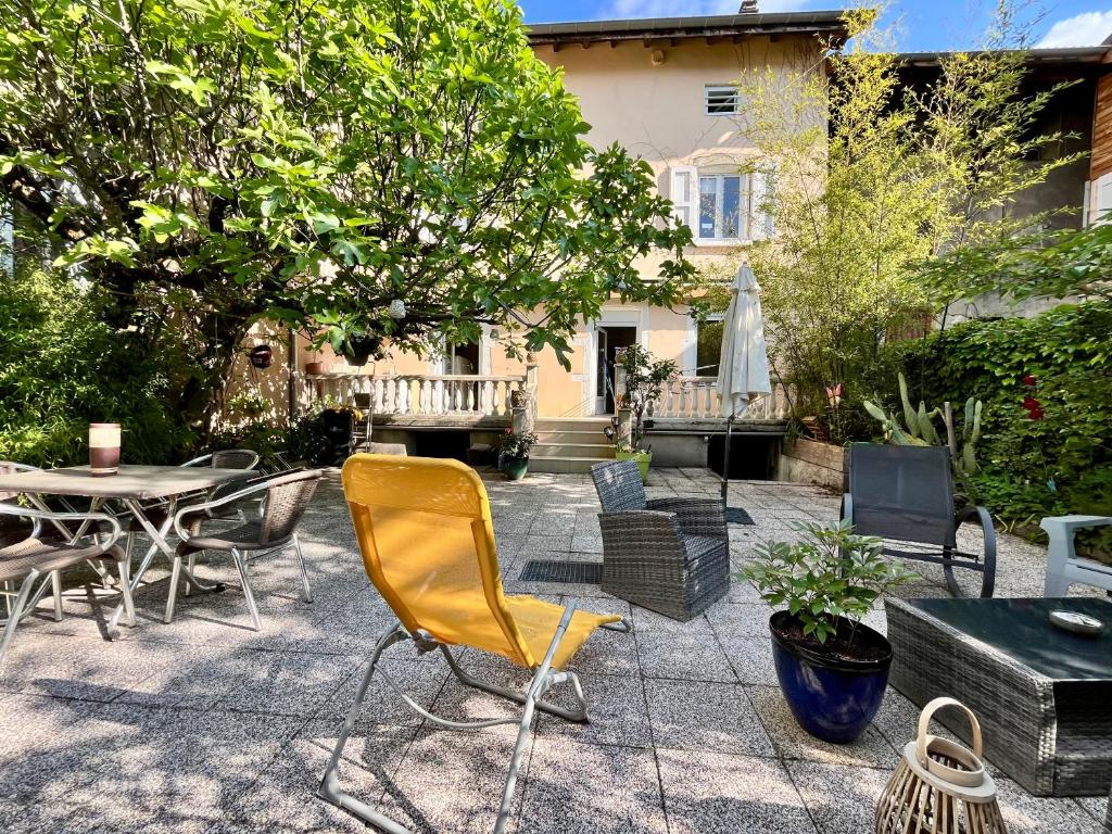 eine Terrasse mit einem gelben Stuhl sowie Tischen und Stühlen in der Unterkunft Le Cosy, accès terrasse de l'établissement in Rives