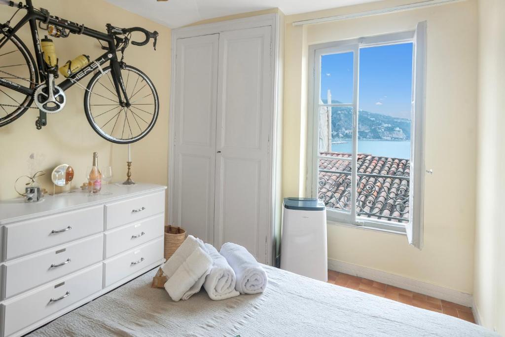 - une chambre avec un lit et un vélo suspendu au mur dans l'établissement Mattoni - Happy Rentals, à Menton