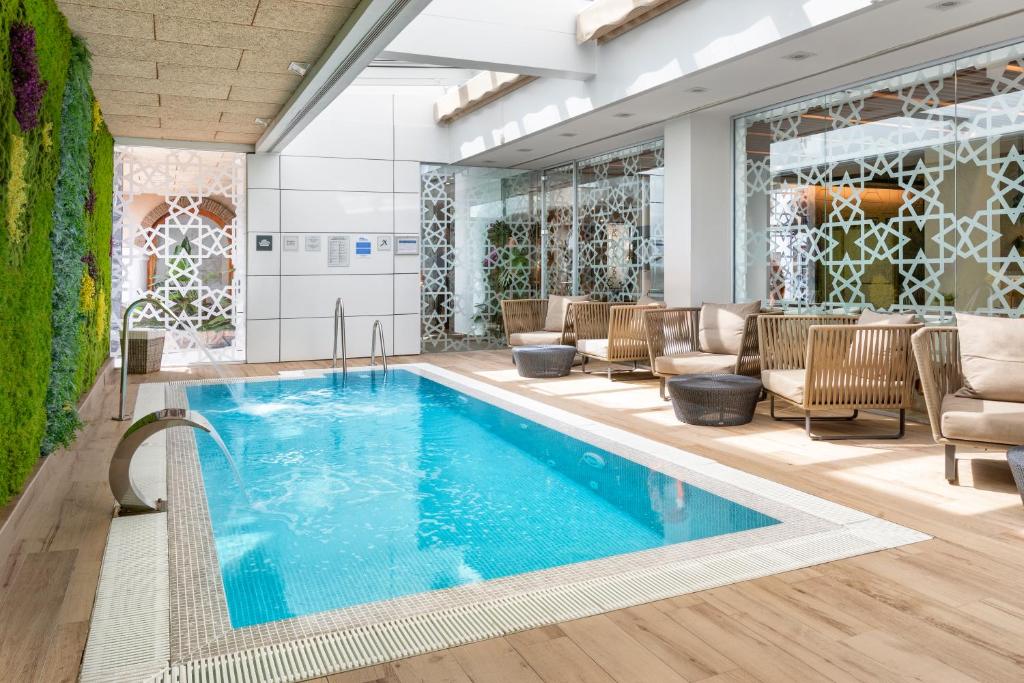 una piscina en el vestíbulo del hotel con sillas y mesa en Catalonia Giralda, en Sevilla