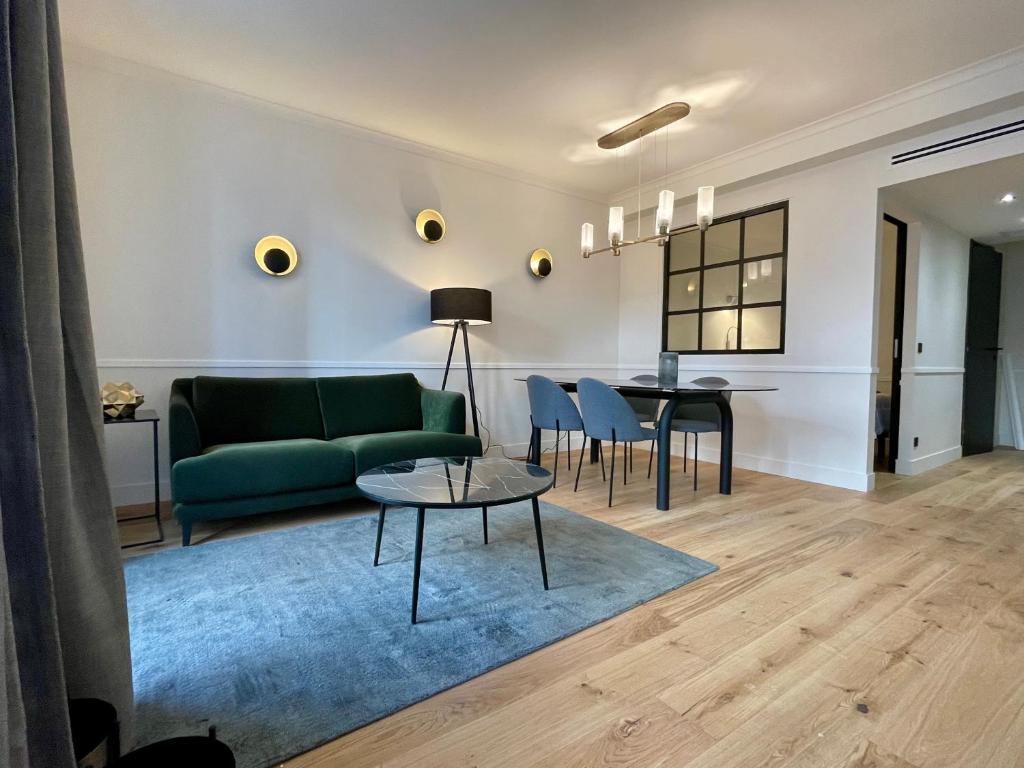 a living room with a green couch and a table at Alfred Suites - Appart's Hôtel - Dijon - Centre Historique in Dijon