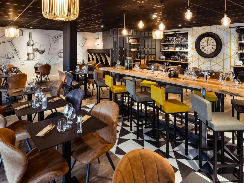 un restaurante con mesas y sillas y un reloj en la pared en Mercure Lyon Est Chaponnay en Chaponnay