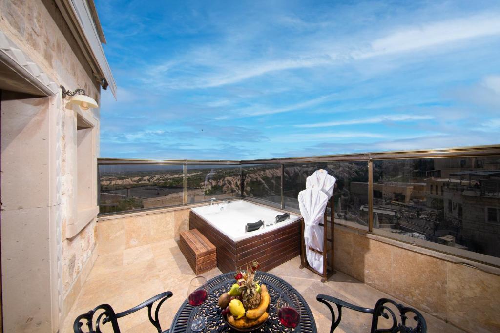 a balcony with a tub and a table with a bowl of fruit at Cappadocia Pegasos Cave Suite Hotel in Uçhisar