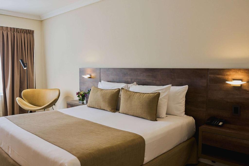 um quarto de hotel com uma cama grande e uma cadeira em Dazzler by Wyndham Buenos Aires San Martin em Buenos Aires