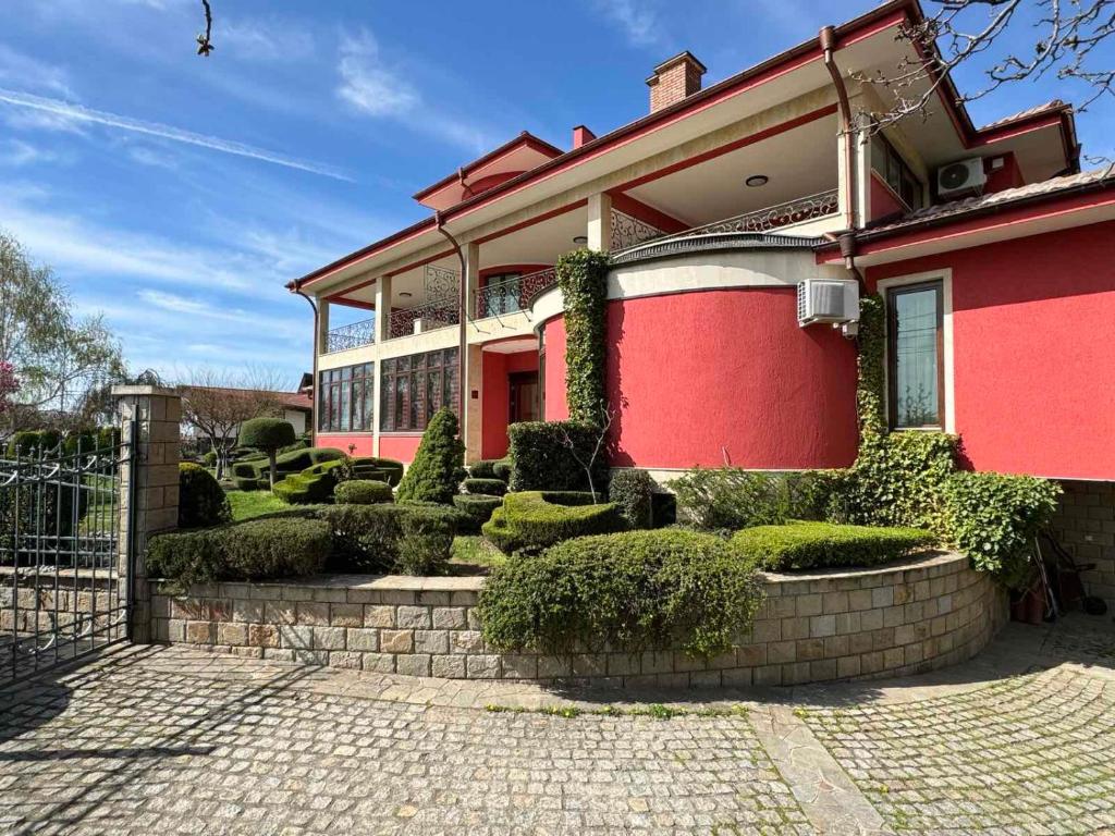 una casa rossa con un mucchio di cespugli davanti di Хотел-ресторант Алмонд a Karlovo