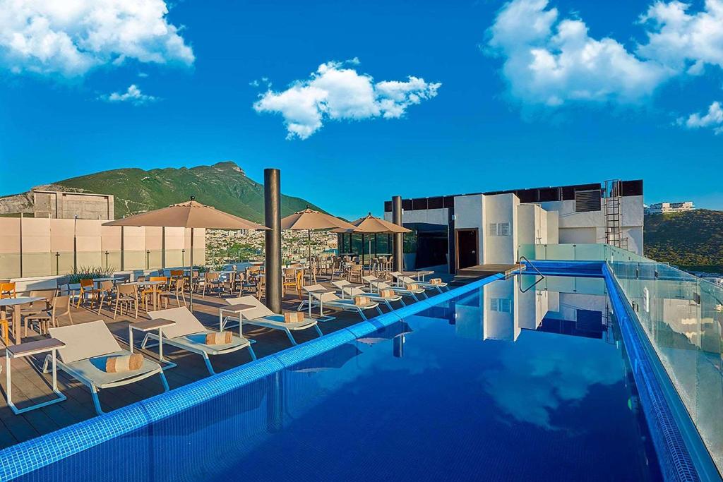 a pool with chairs and umbrellas on a hotel at Radisson Hotel Monterrey San Jeronimo in Monterrey
