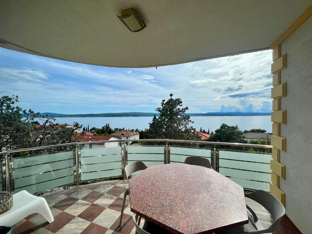 einen Balkon mit einem Tisch und Blick auf das Wasser in der Unterkunft Apartment Picturesque Retreat in Dramalj