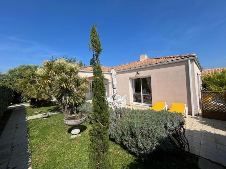 une maison avec deux chaises jaunes et une cour dans l'établissement Les Sables d'Olonne, villa de charme, conviviale, idéale en famille ou entre amis - jacuzzi intérieur, à Olonne-sur-Mer