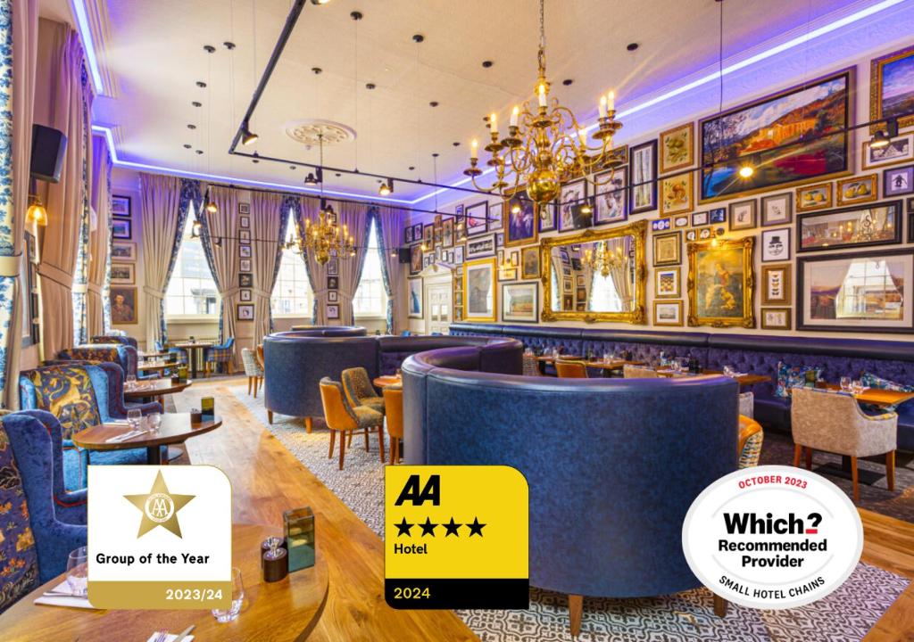 een restaurant met een bar met blauwe stoelen en foto's aan de muren bij The Rutland Arms Hotel, Bakewell, Derbyshire in Bakewell