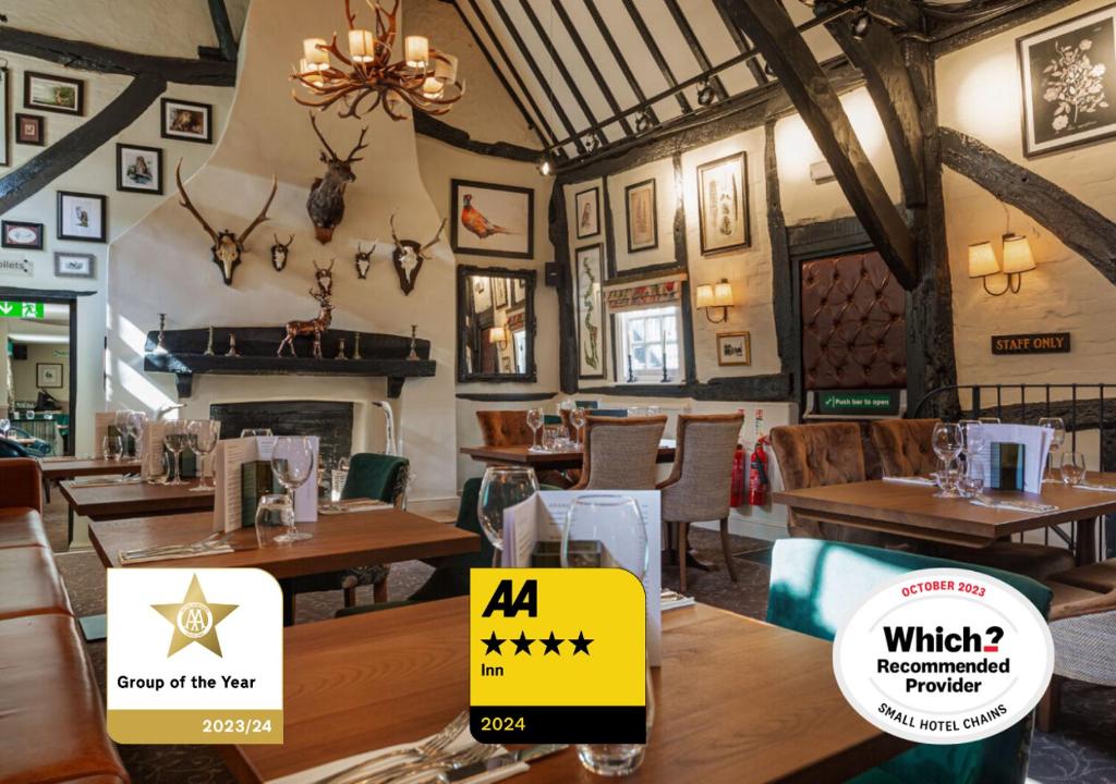 un restaurante con mesas y sillas de madera y una lámpara de araña en The George Hotel, Dorchester-on-Thames, Oxfordshire en Dorchester on thames