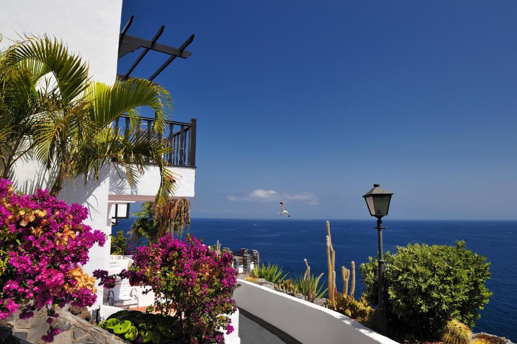 a view of the ocean from a house with flowers at Hotel Jardín Tecina in Playa de Santiago