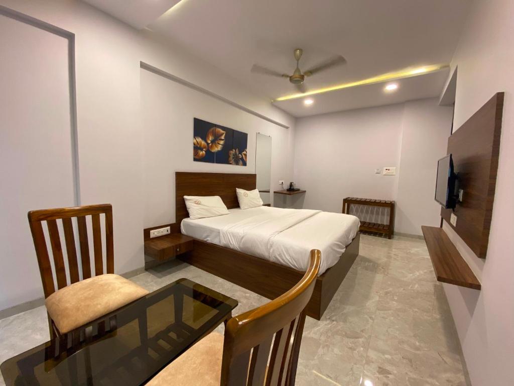 Super OYO Flagship Hotel Swaraj في Pālghar: غرفة نوم بسرير وطاولة وتلفزيون