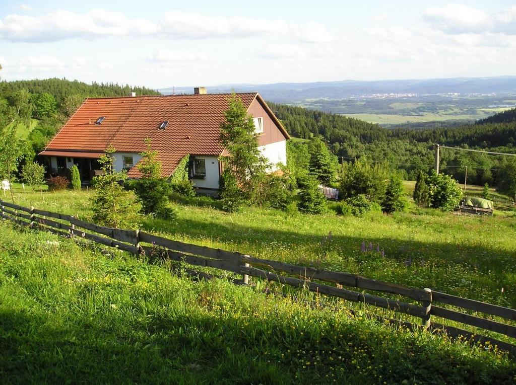 una casa in cima a una collina erbosa con una recinzione di MariePavla a Jáchymov