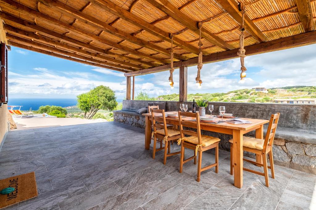 jadalnia na świeżym powietrzu z drewnianym stołem i krzesłami w obiekcie Sa Domo Isola Rossa w mieście Trinità dʼAgultu