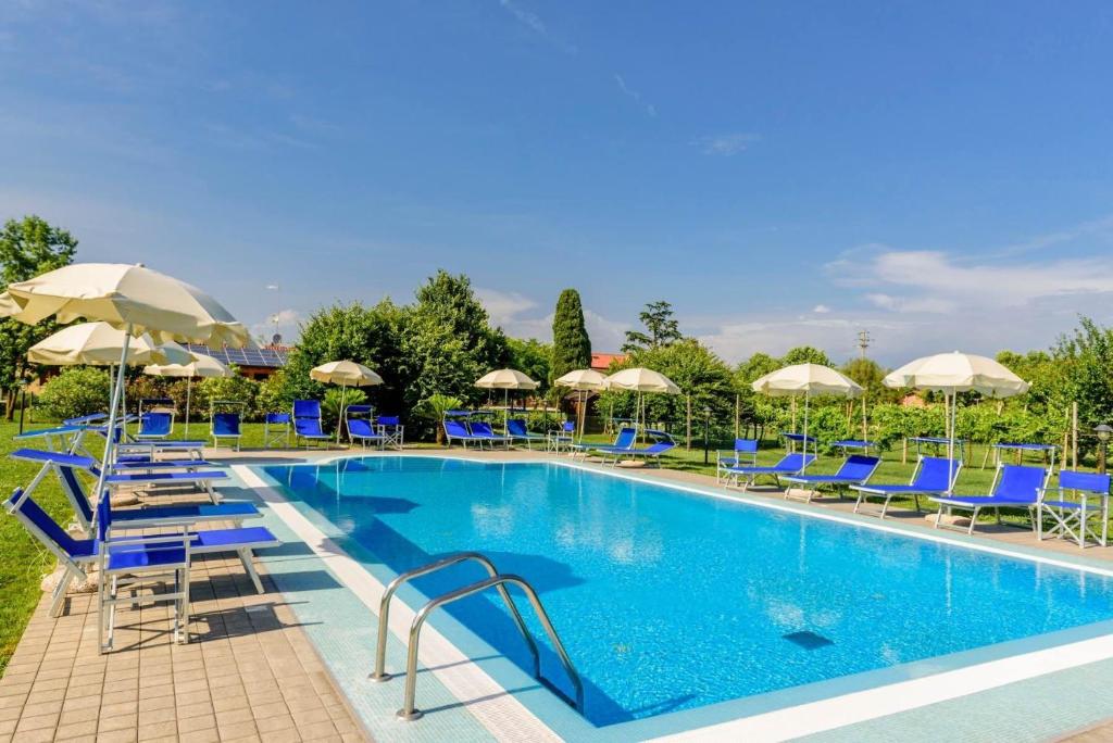 una grande piscina con sedie blu e ombrelloni di Luxury Lodge Glamping a Palazzolo dello Stella