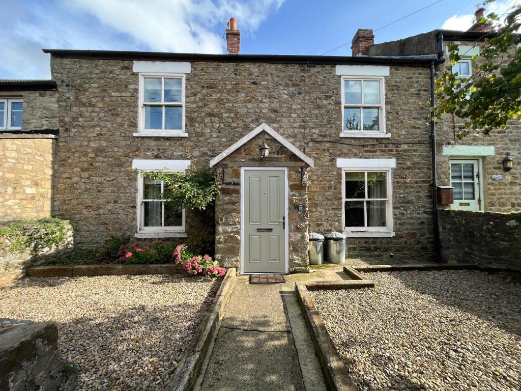 een stenen huis met een deur aan de voorkant bij Wensleydale Stone Cottage in Hunton